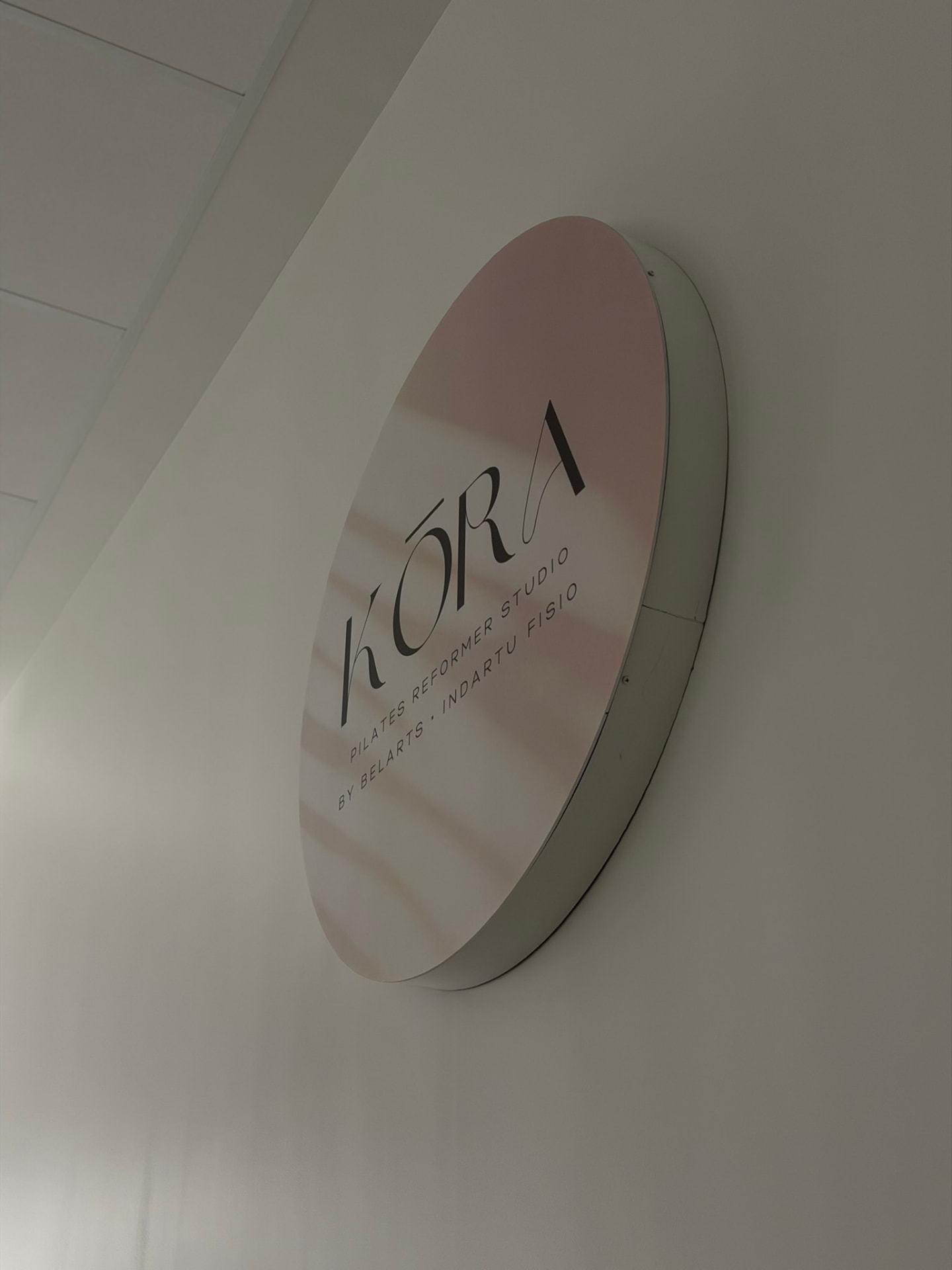 Rótulo circular de KŌRA Pilates Reformer Studio visto en escorzo